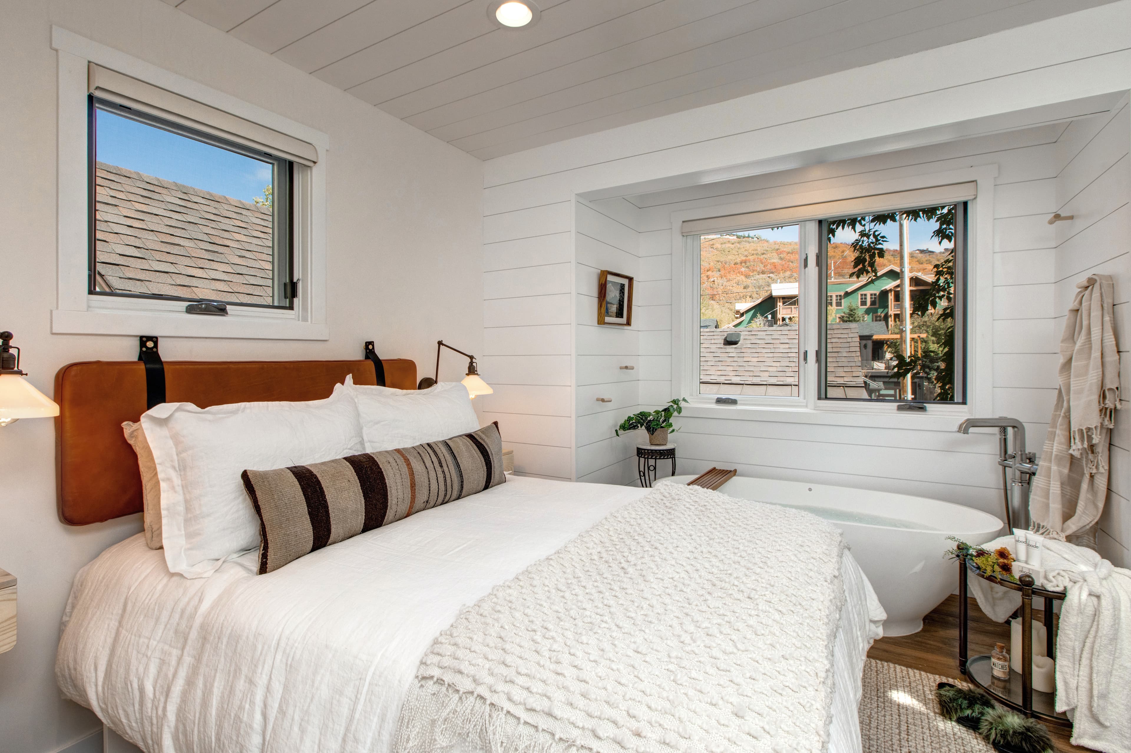 Lofted bedroom in detached guest suite, with a queen bed next to standalone bathtub.