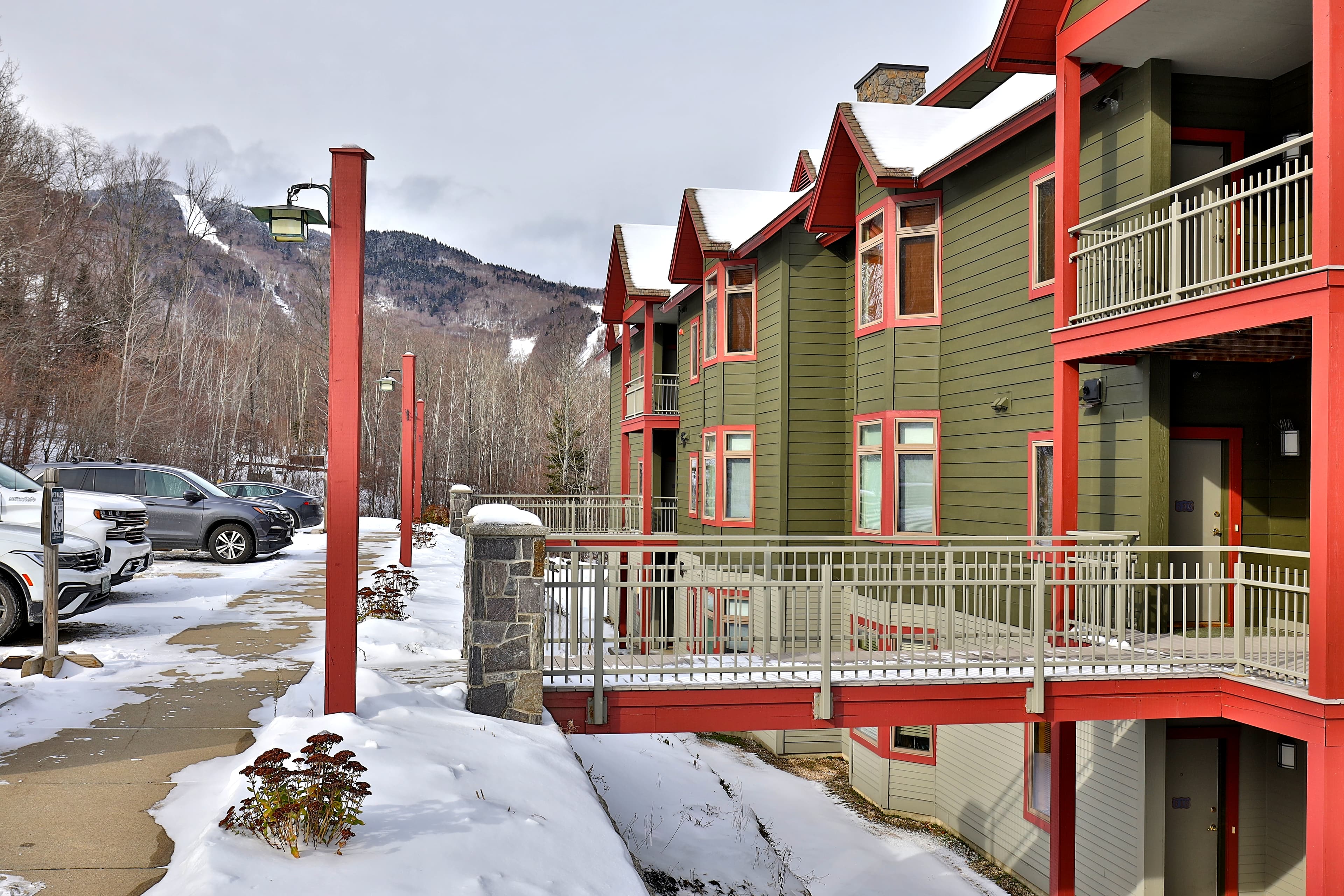 Snow-covered exterior of The Lodges with guest parking and mountain views. Convenient location for winter adventures and a welcoming alpine-style design.