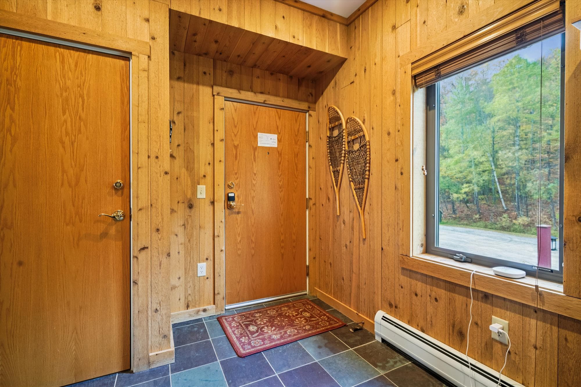 Inviting entryway featuring rustic wood walls, slate tile underfoot, and soft natural light from the large window. The perfect transition from the outdoors to your relaxing mountain retreat.