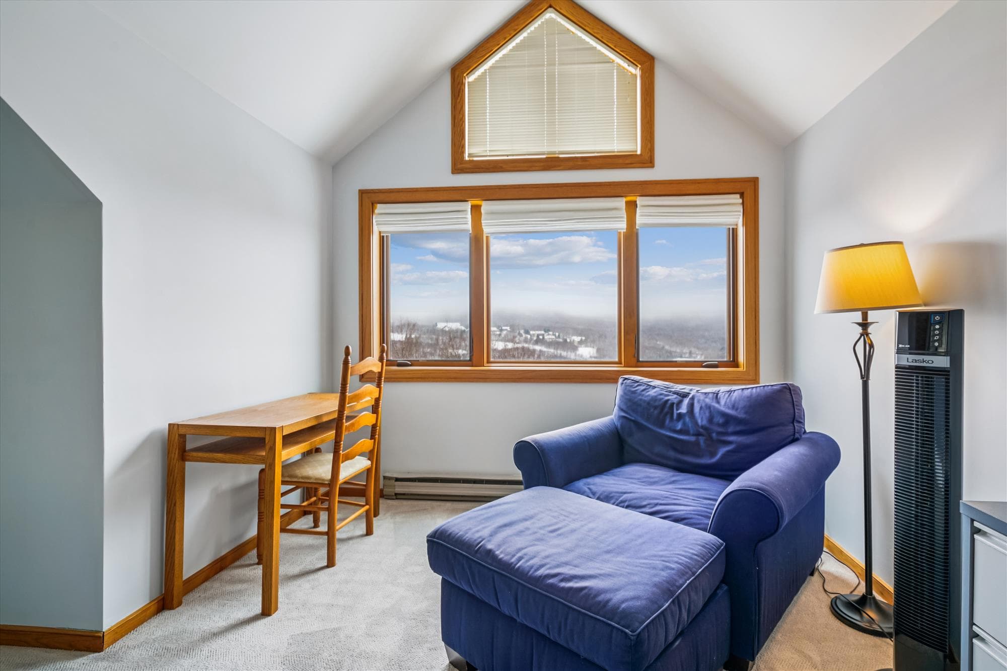 Quiet sitting area with a comfortable chair, small desk, and beautiful mountain views through the large windows.