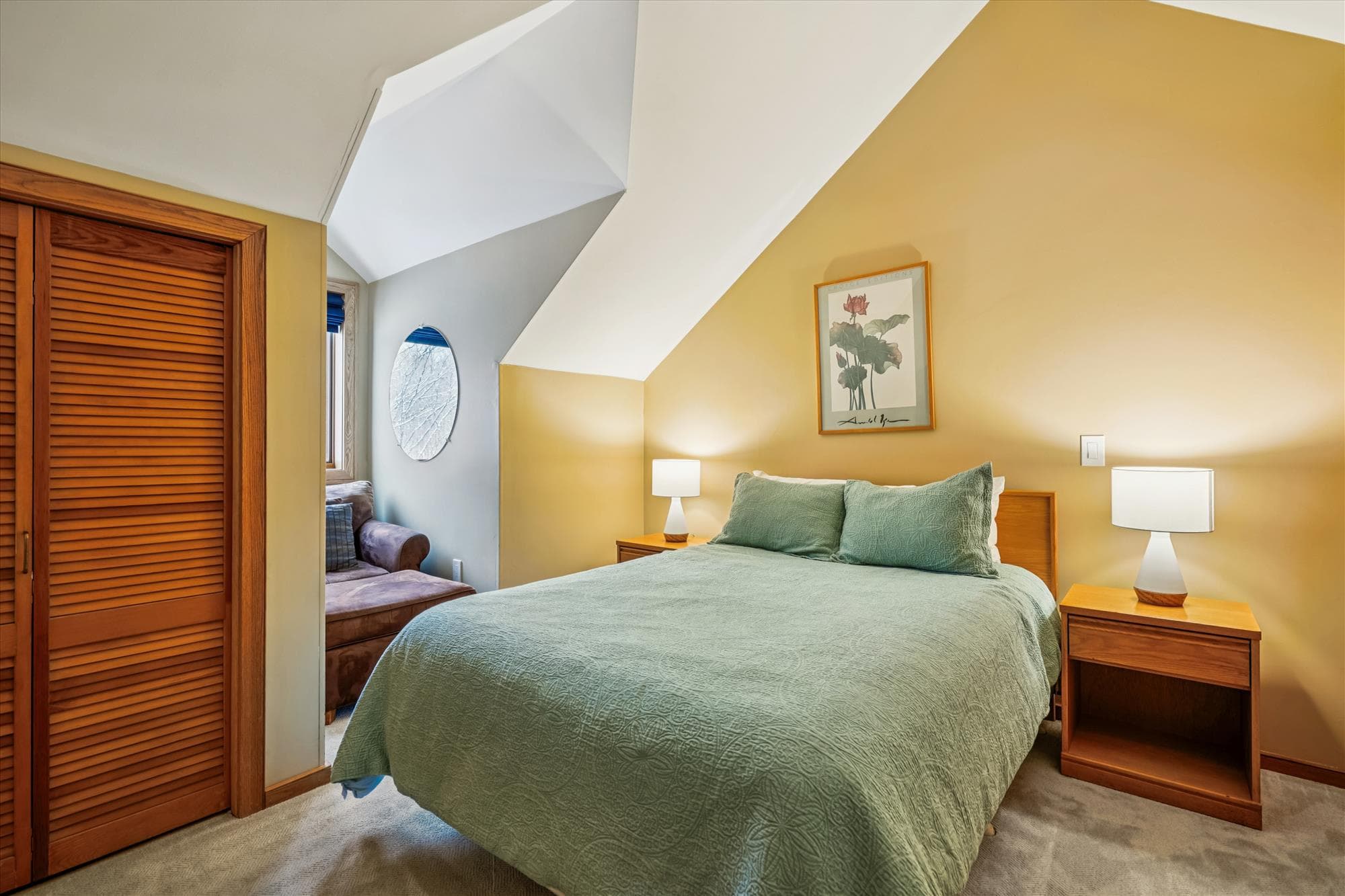 Spacious upstairs bedroom featuring a queen bed, vaulted ceilings, and bedside tables with lamps.