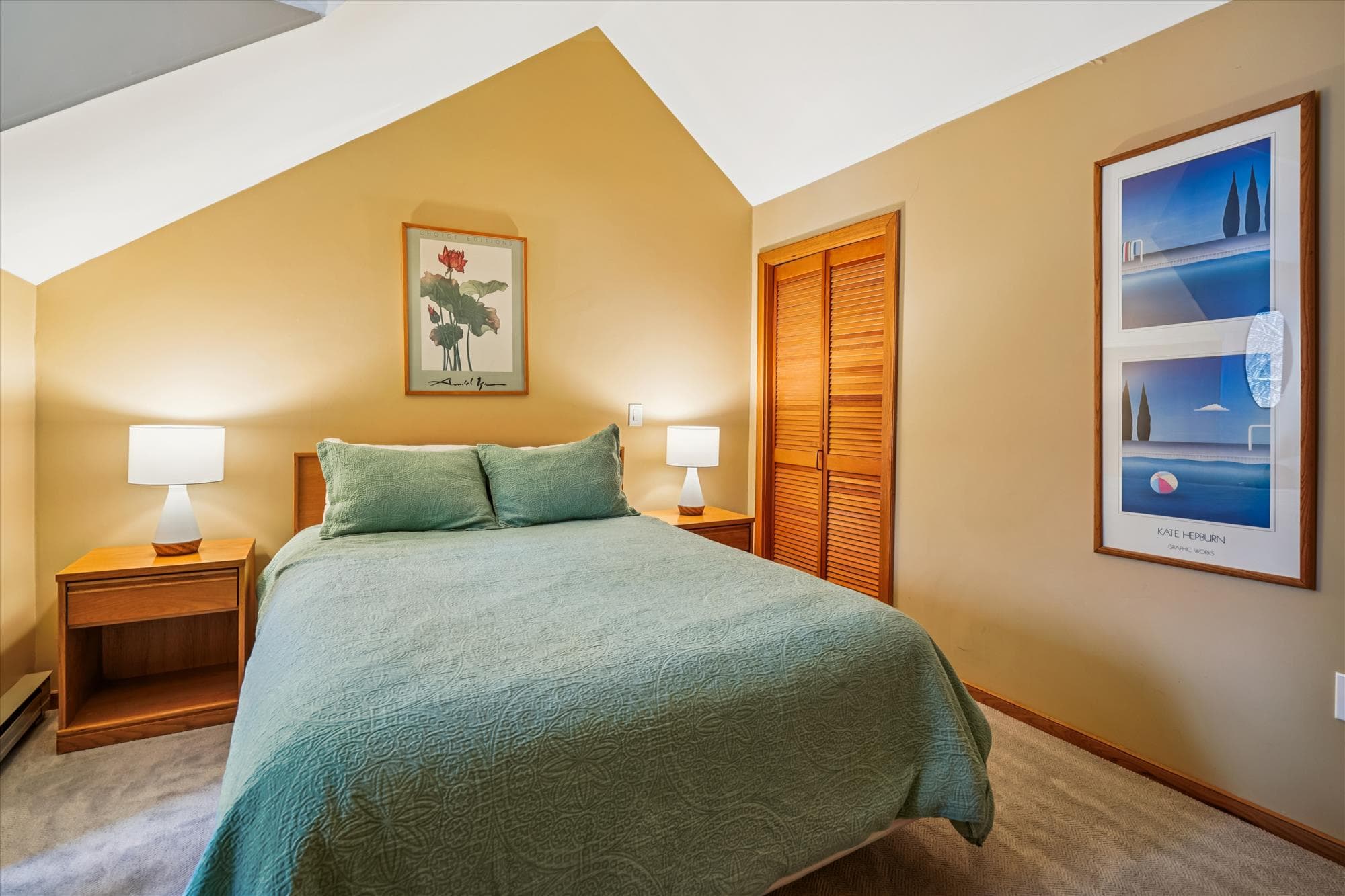 Airy upstairs bedroom with a queen bed, warm wood furnishings, and natural light.