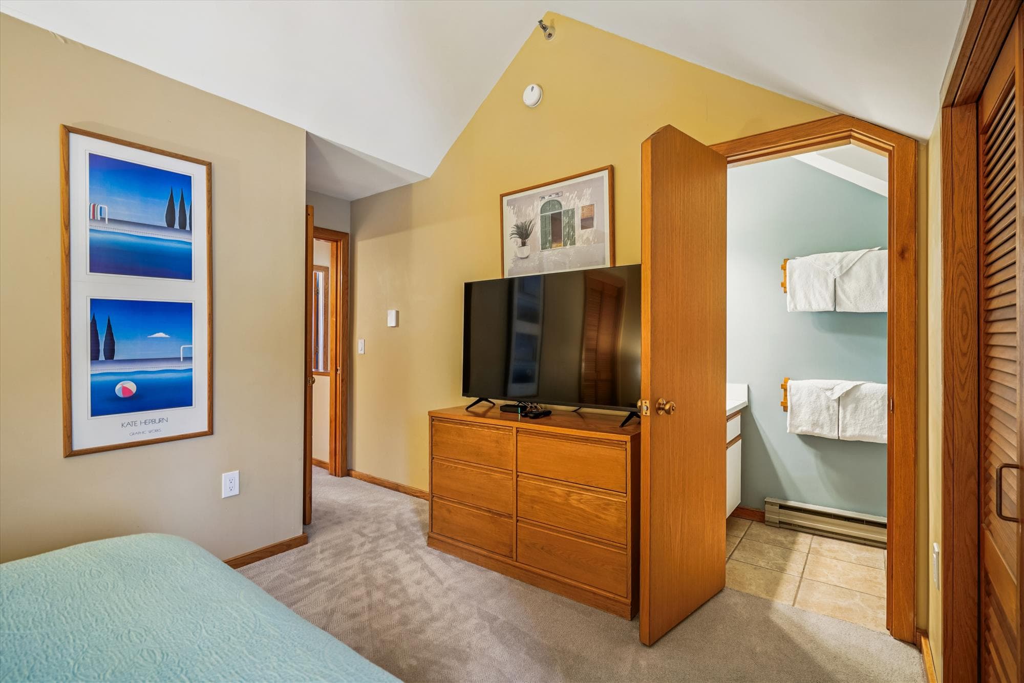 Queen bedroom with dresser, TV, and convenient access to the attached bathroom.