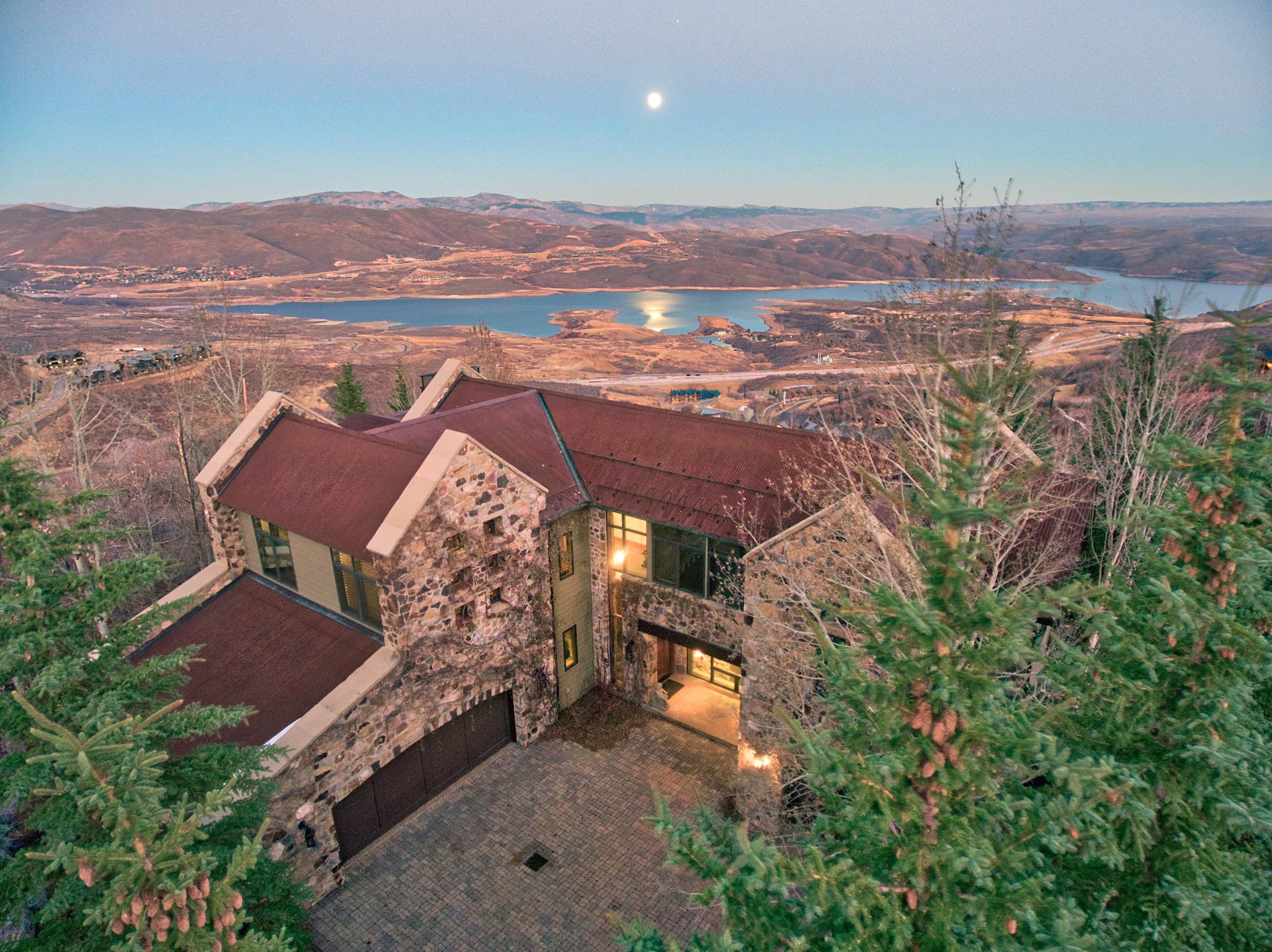 Exterior of mountain home at dusk with lake and moonlit sky in the background.