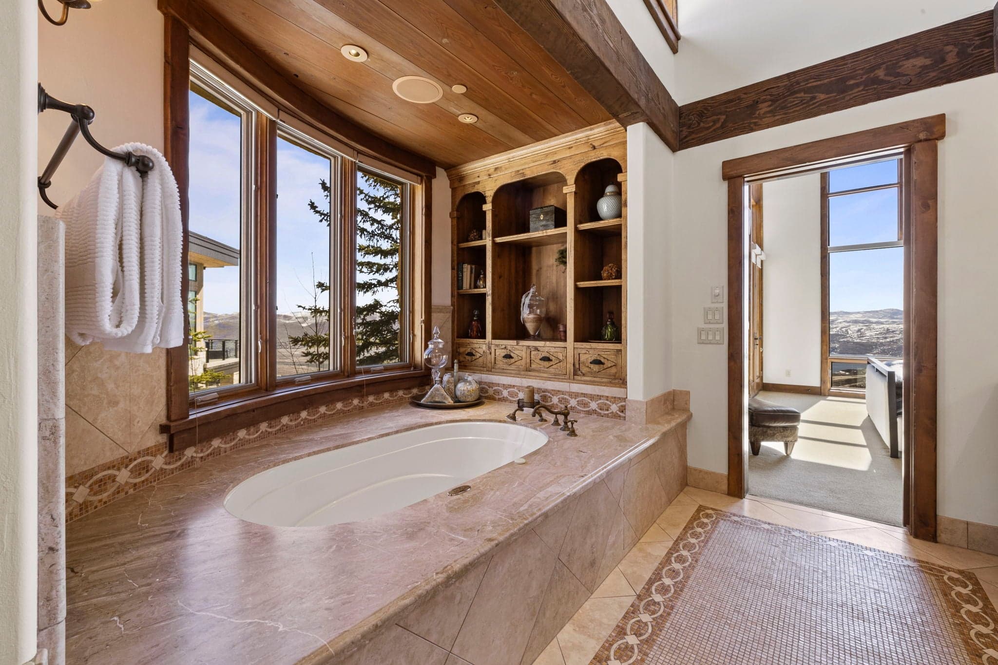 Spa-style bathroom with soaking tub, large windows, and mountain views.