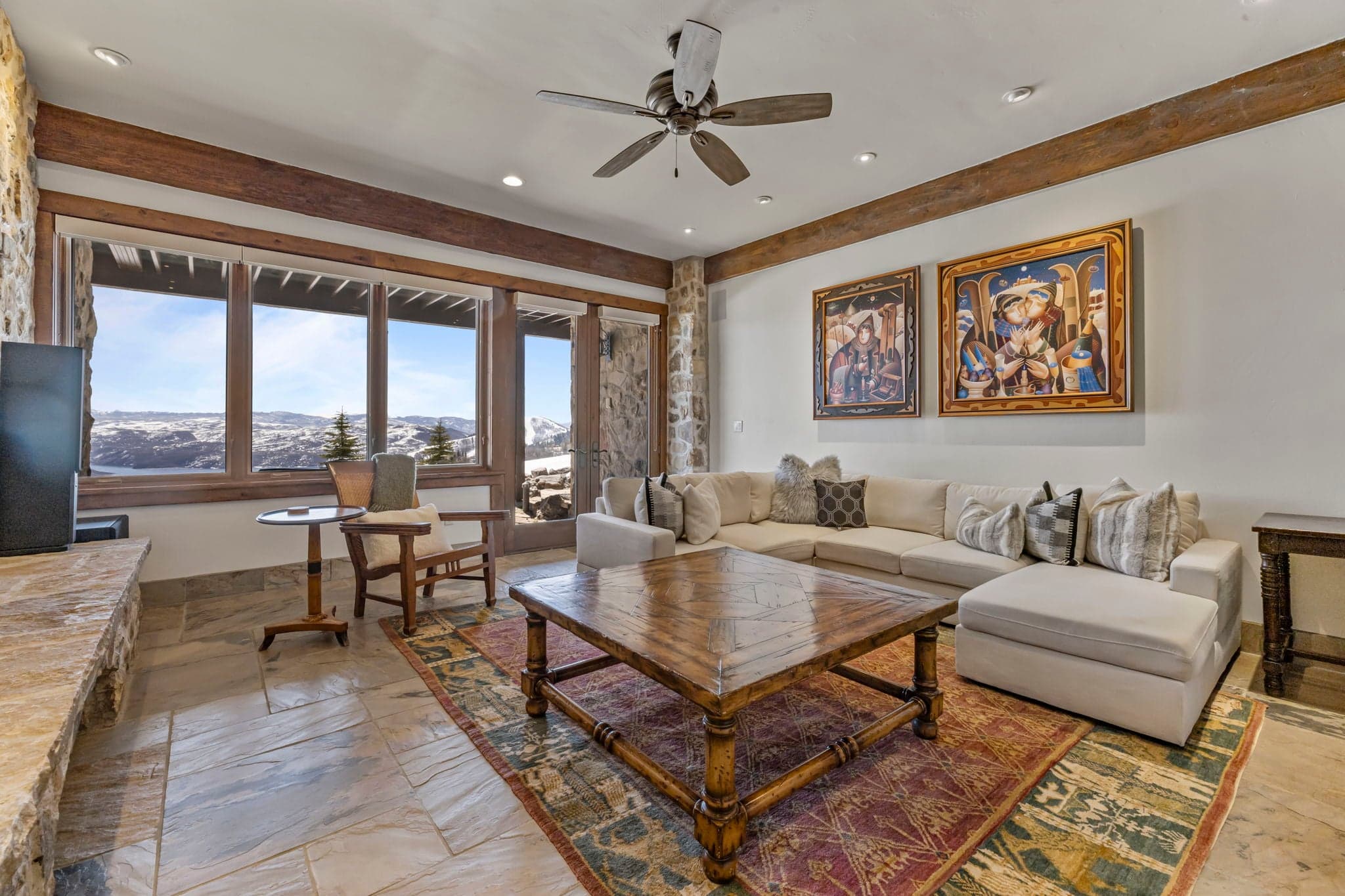 Lower-level living room with sectional sofa, desk, and large windows with mountain views.
