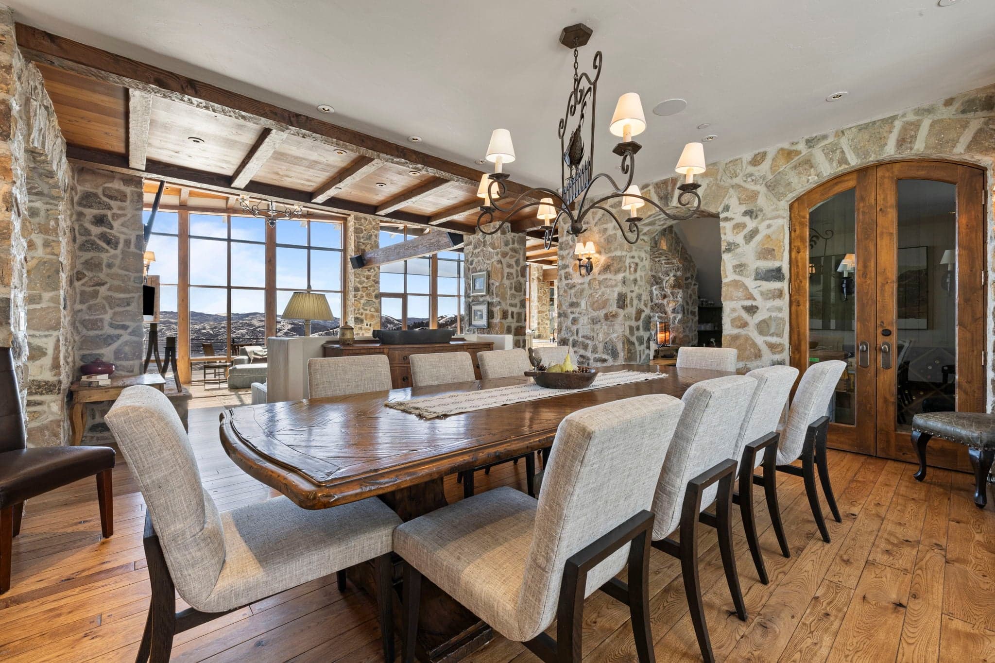 Additional dining space with rustic stone walls, chandelier, and large windows.