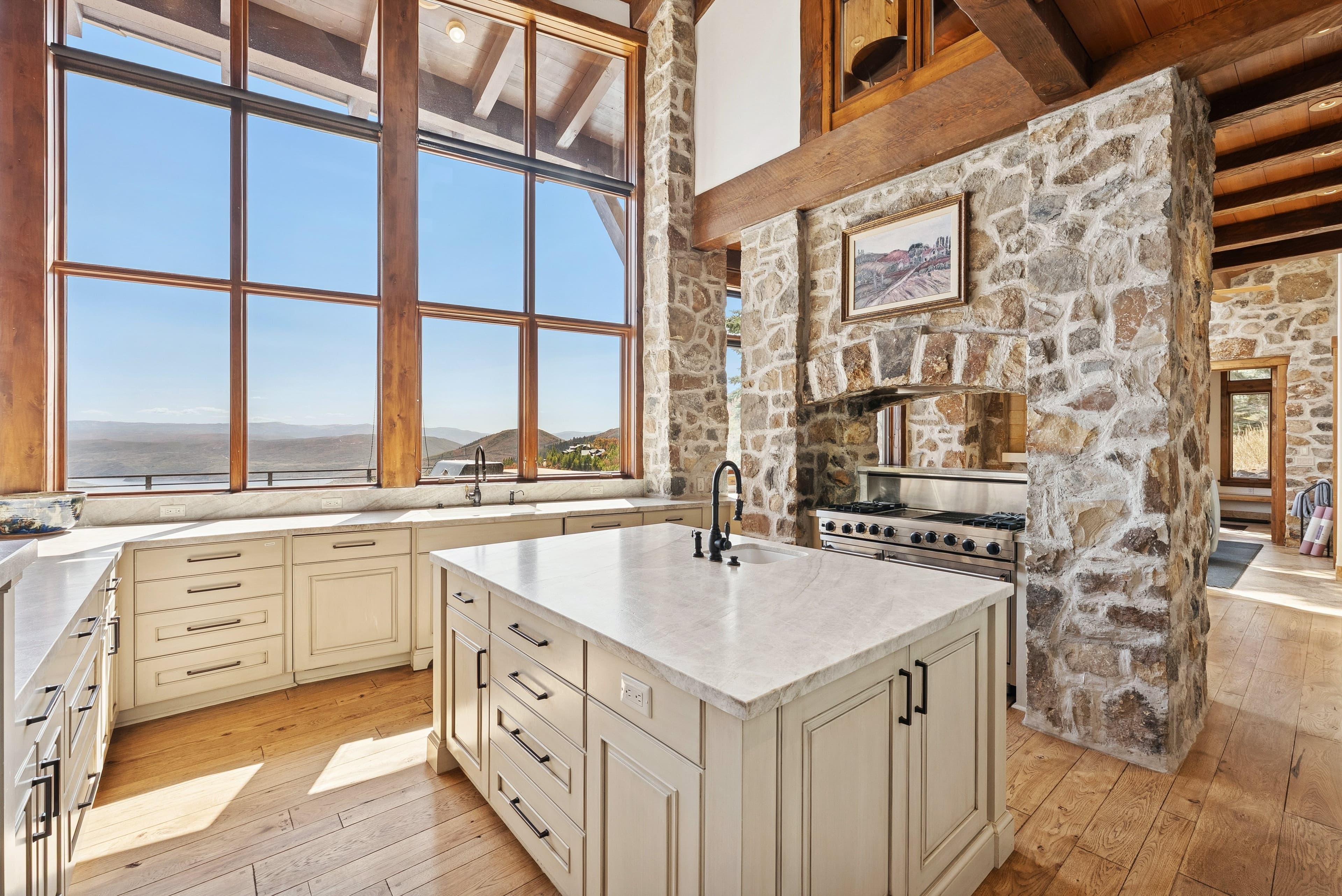 Kitchen island with sink and expansive windows offering mountain views.