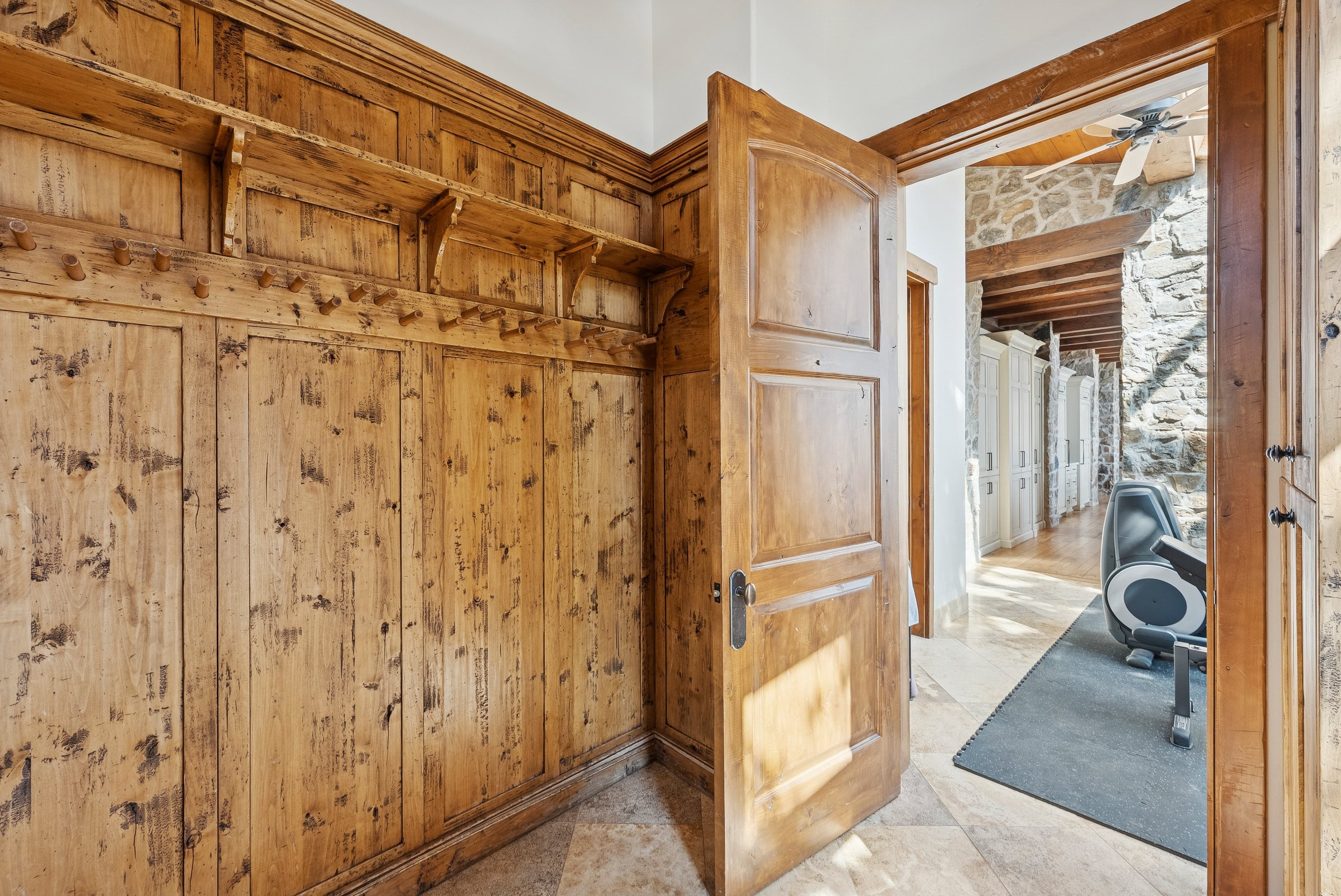 Hallway with rustic wood doors leading into a mountain home gym.