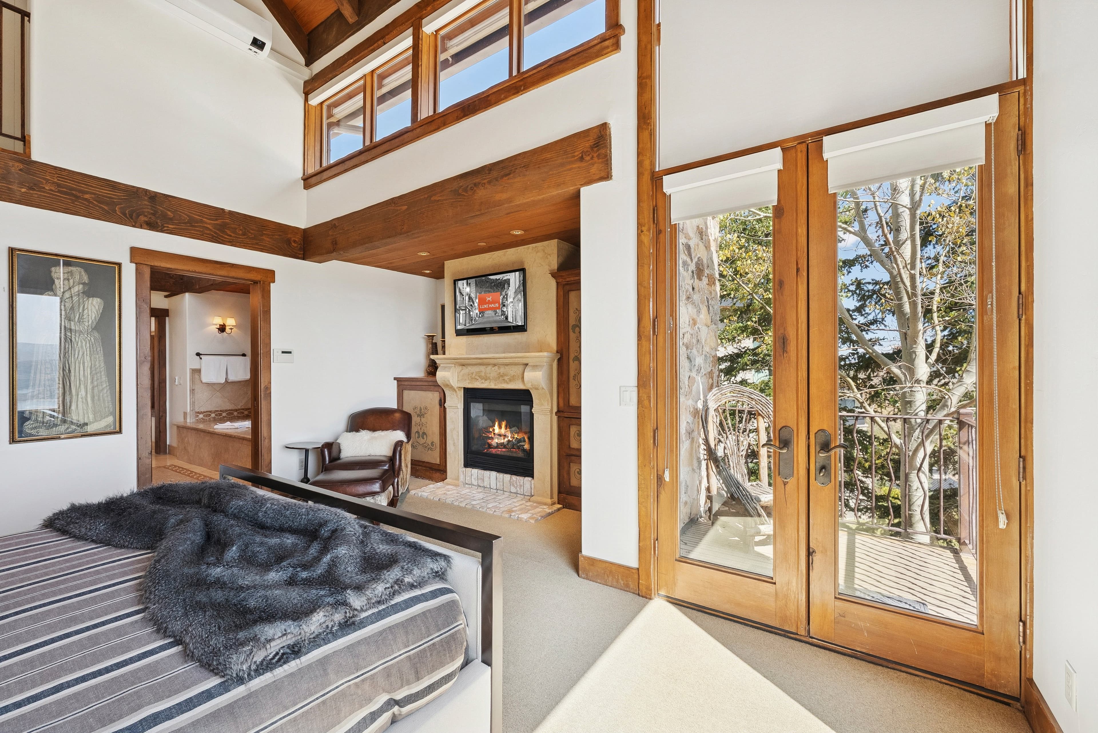 Primary suite with fireplace, vaulted ceiling, and private balcony access.