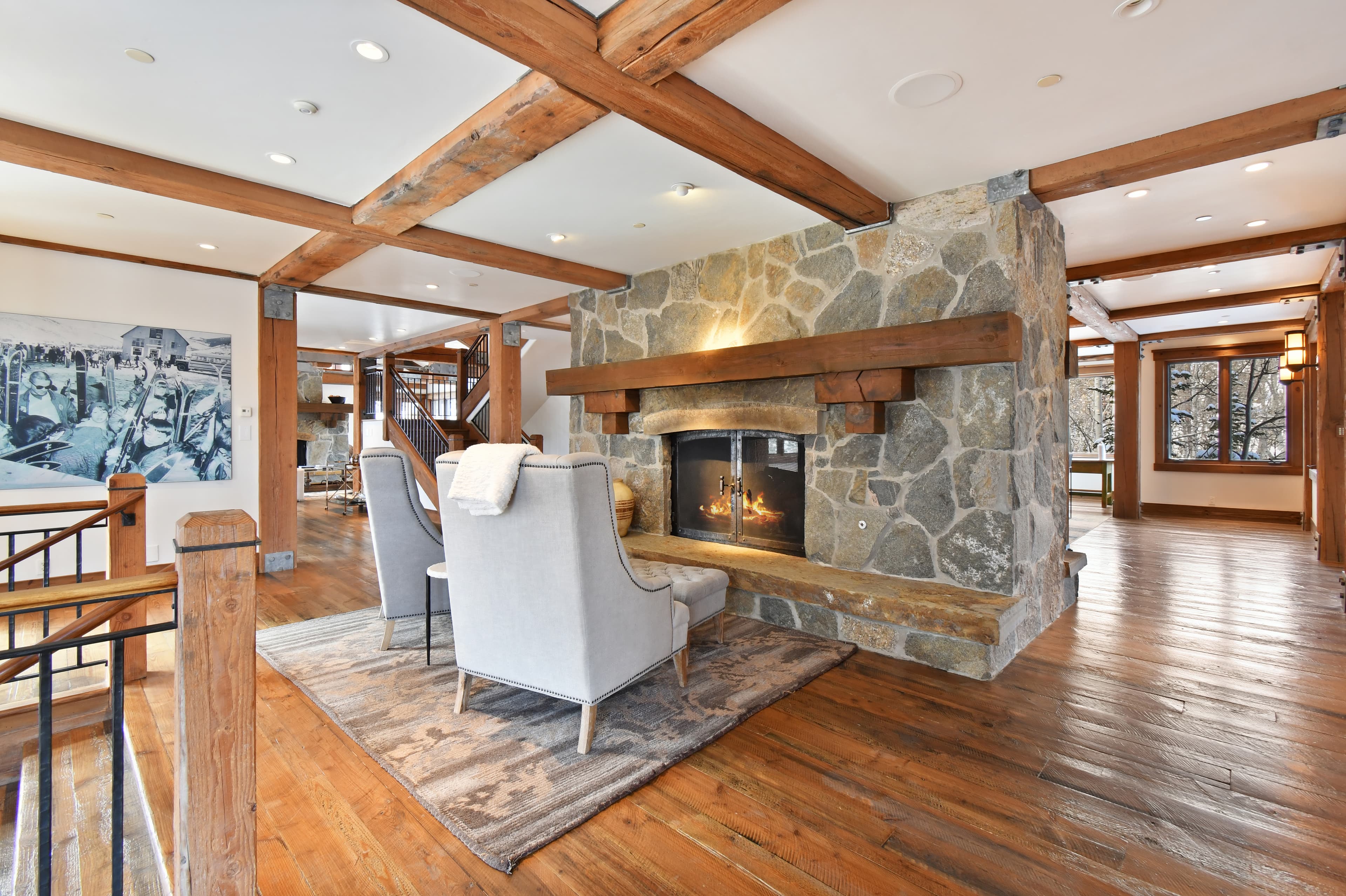 Two cushioned chairs sit in front of a small fireplace built into the center of a room.