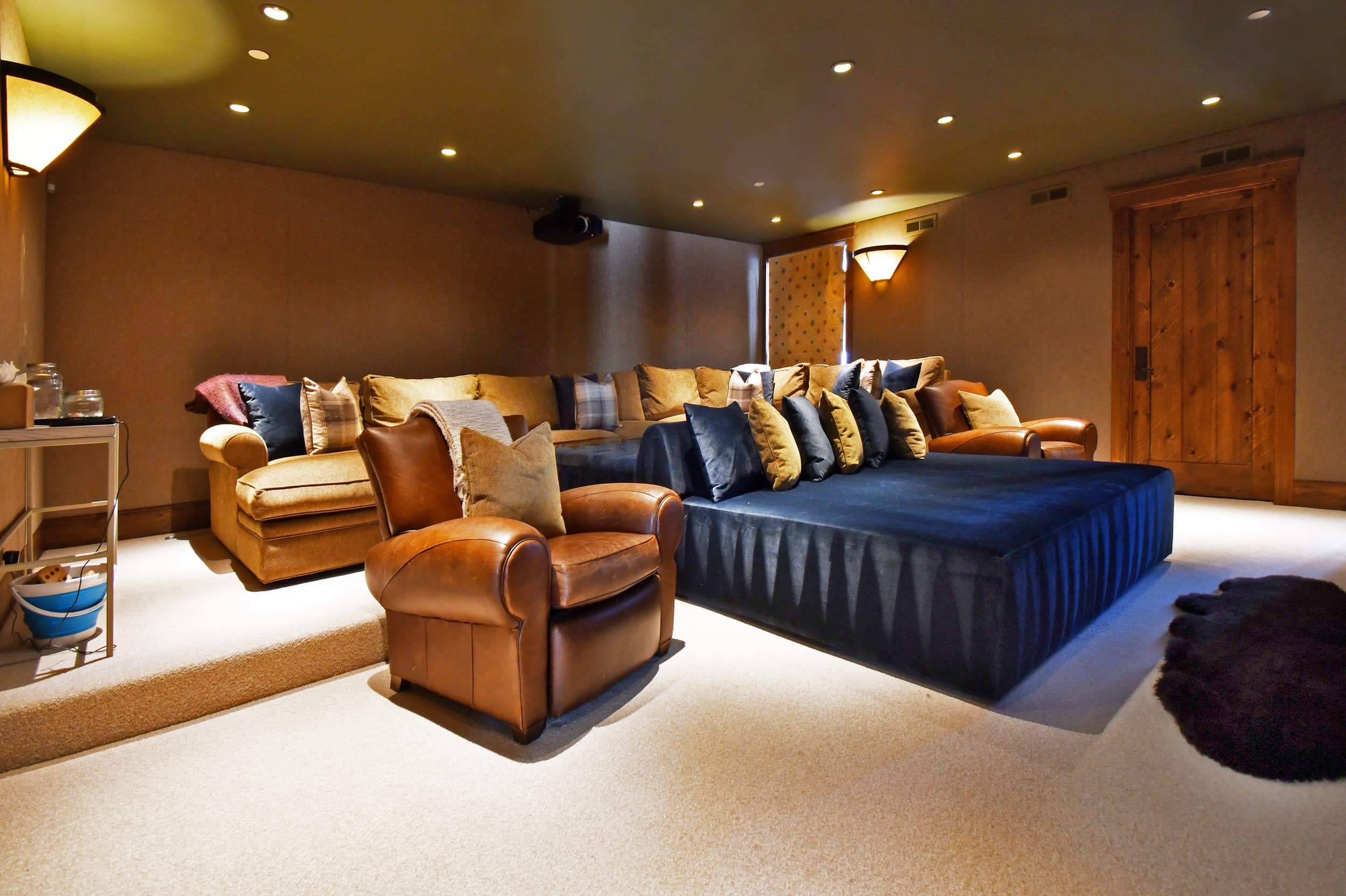 Large couches and armchairs flank a bed in the center of the media room.