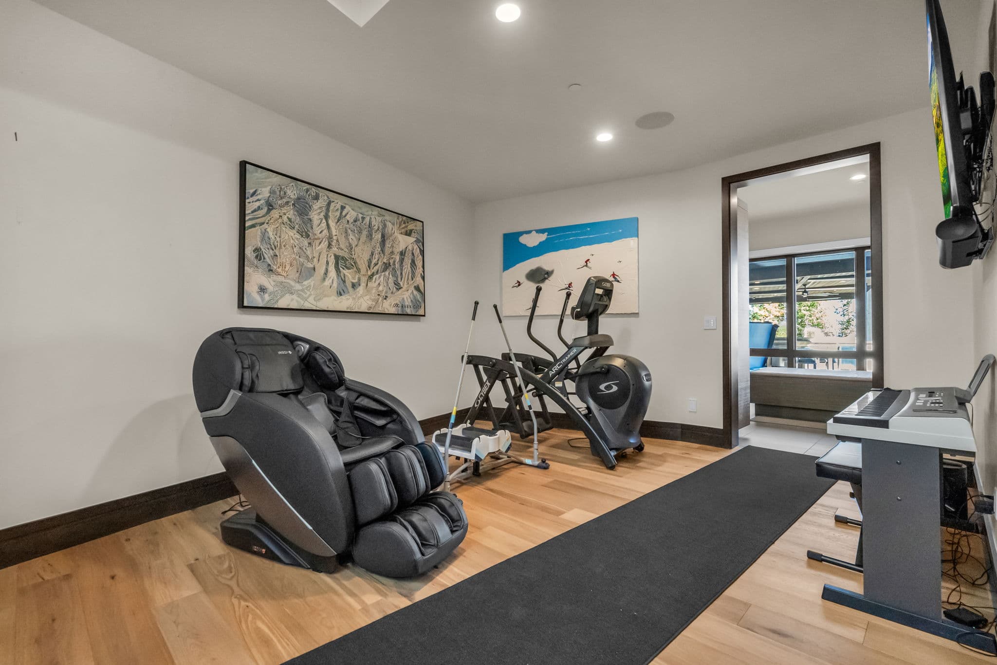 Fitness Room with a Massage Chair, an Elliptical Machine and TV