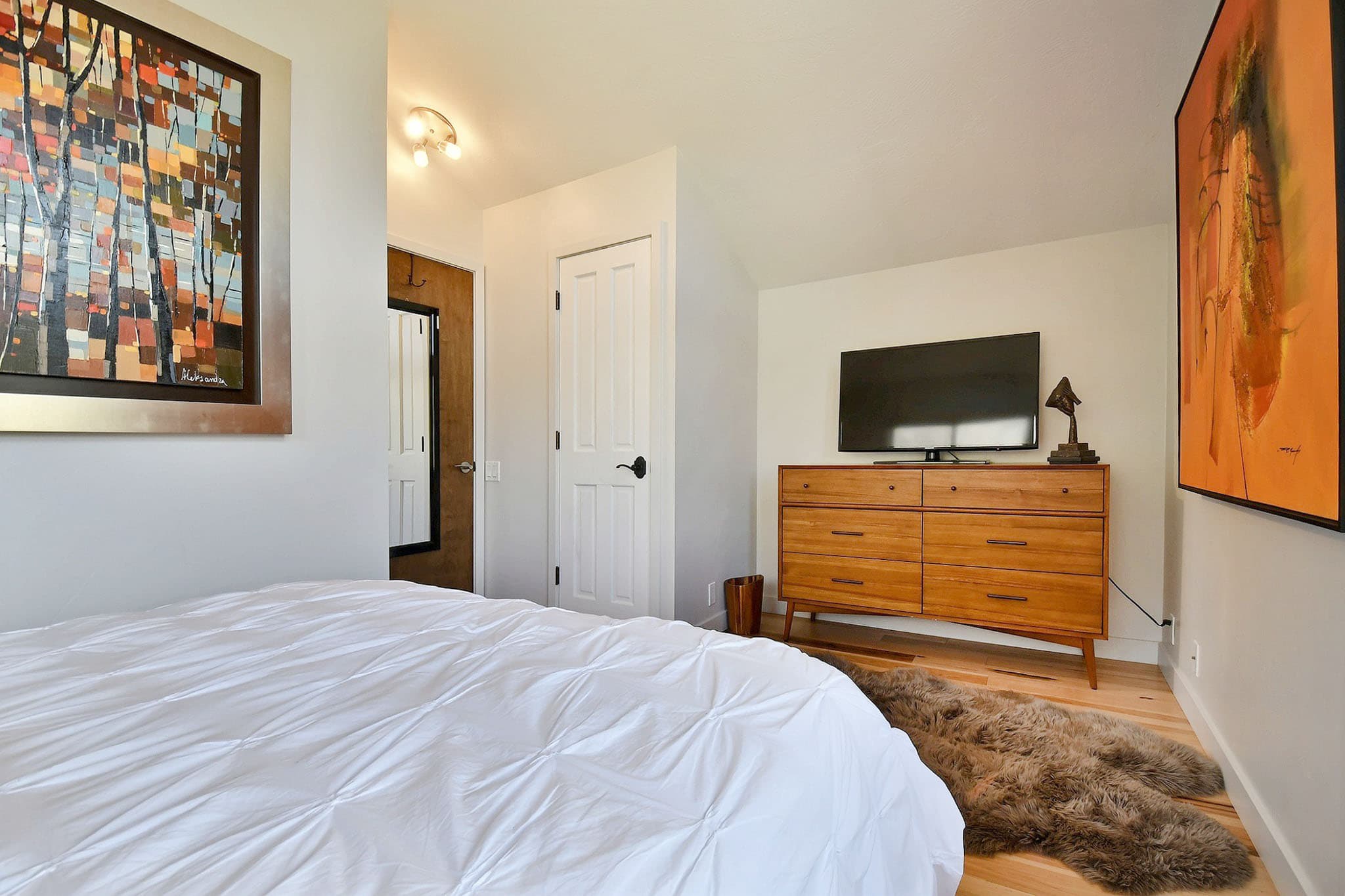 Bed with White Cover, Dresser, TV, and Painting