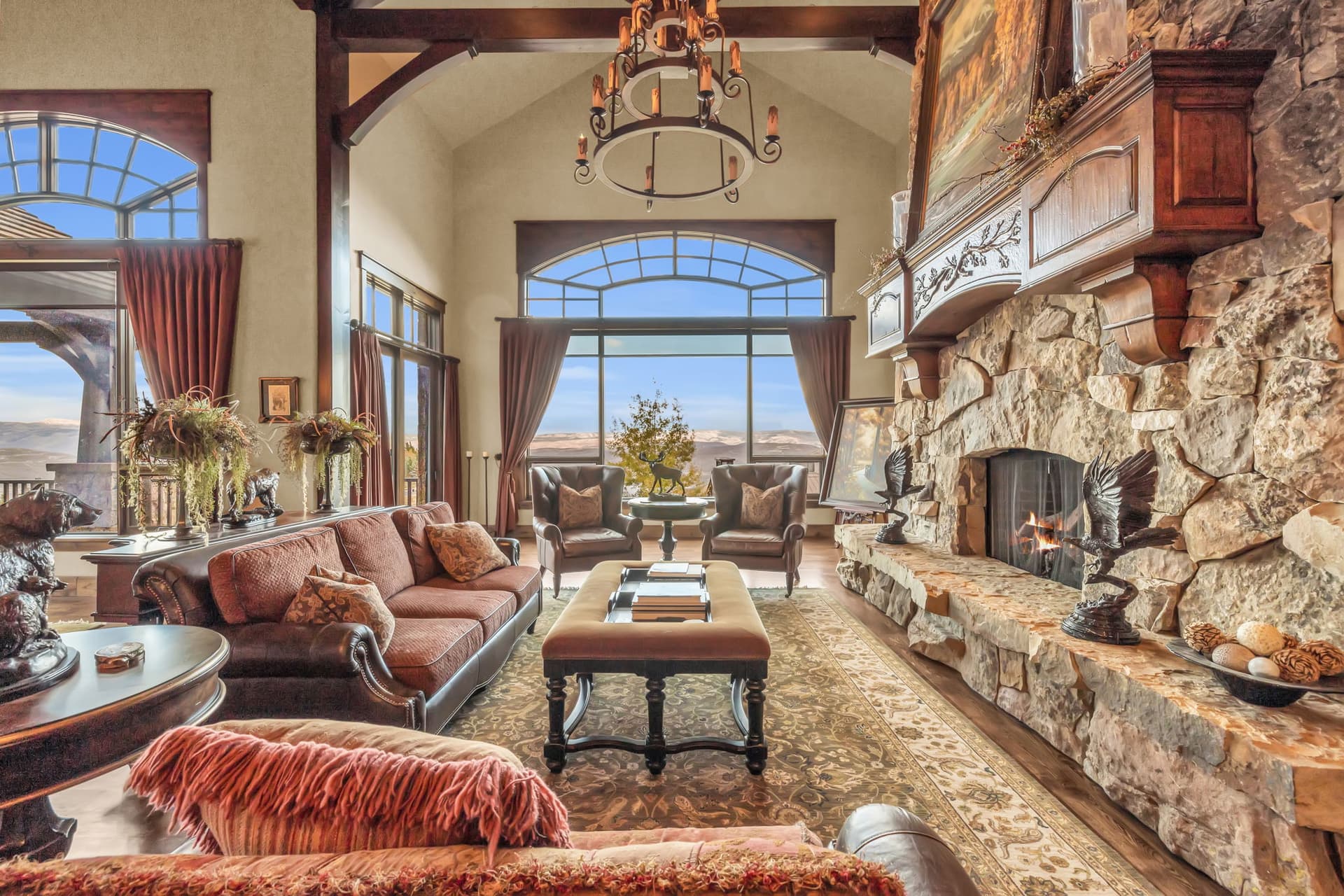 Grand fireplace with paintings and comfortable couches, plus a chandelier.