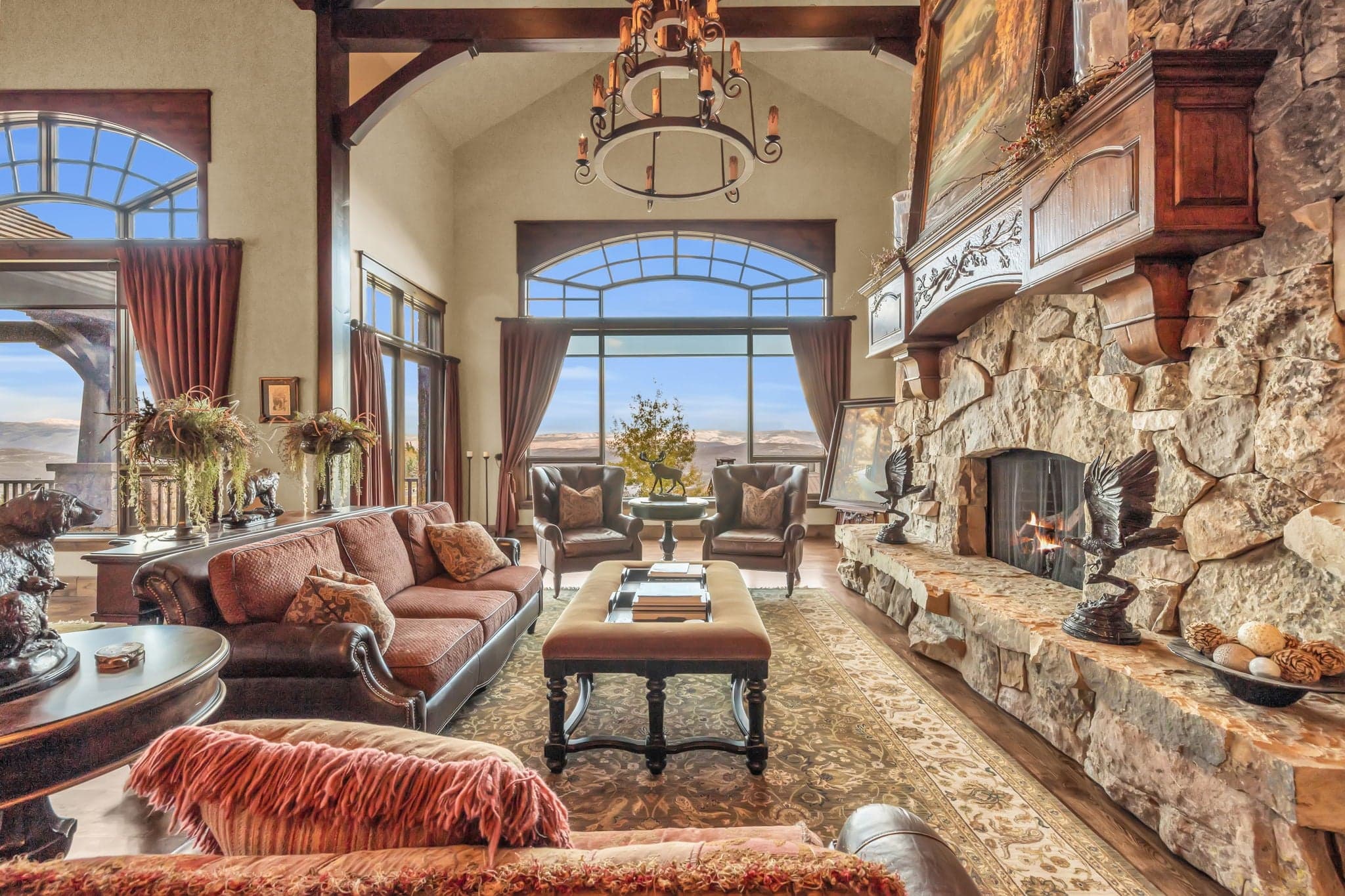 Grand fireplace with paintings and comfortable couches, plus a chandelier.