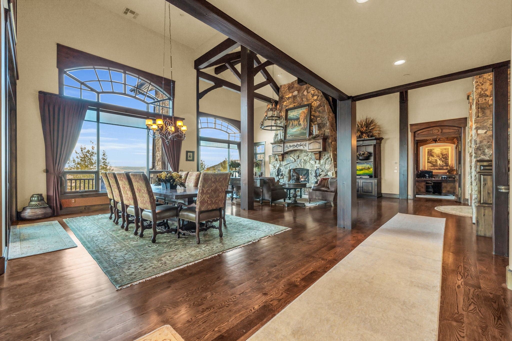 Spacious living room  with paintings, chandelier, dining room, and fireplace.