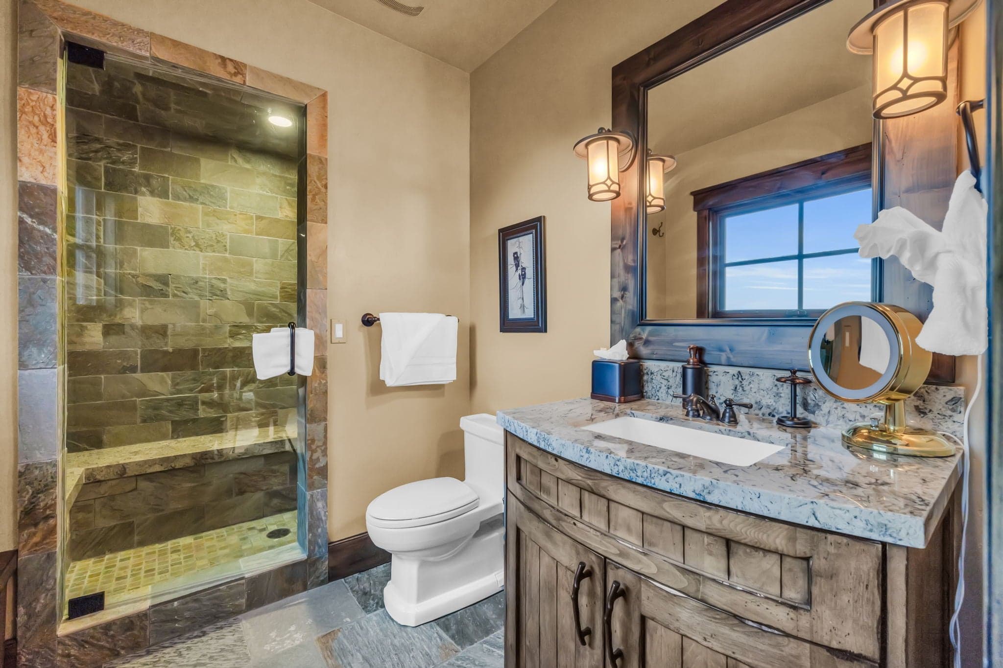 Bathroom with a toilet, sink, mirror and shower.