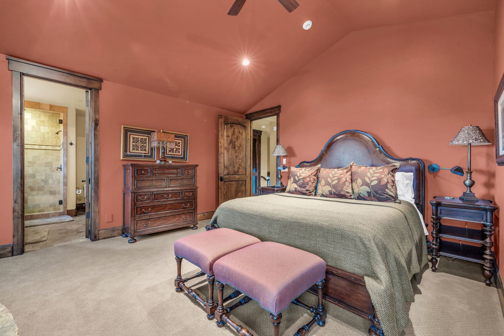 Bedroom with Queen sized mattress, bathroom, two ottomans, dresser, and nightstand.