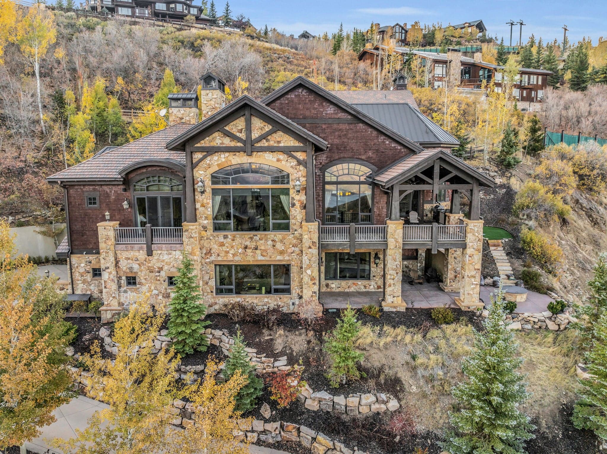 A view of the front of Morning Star, a home in Deer Valley. The outside has wood shingles and stone siding, you can see the top deck with views inside