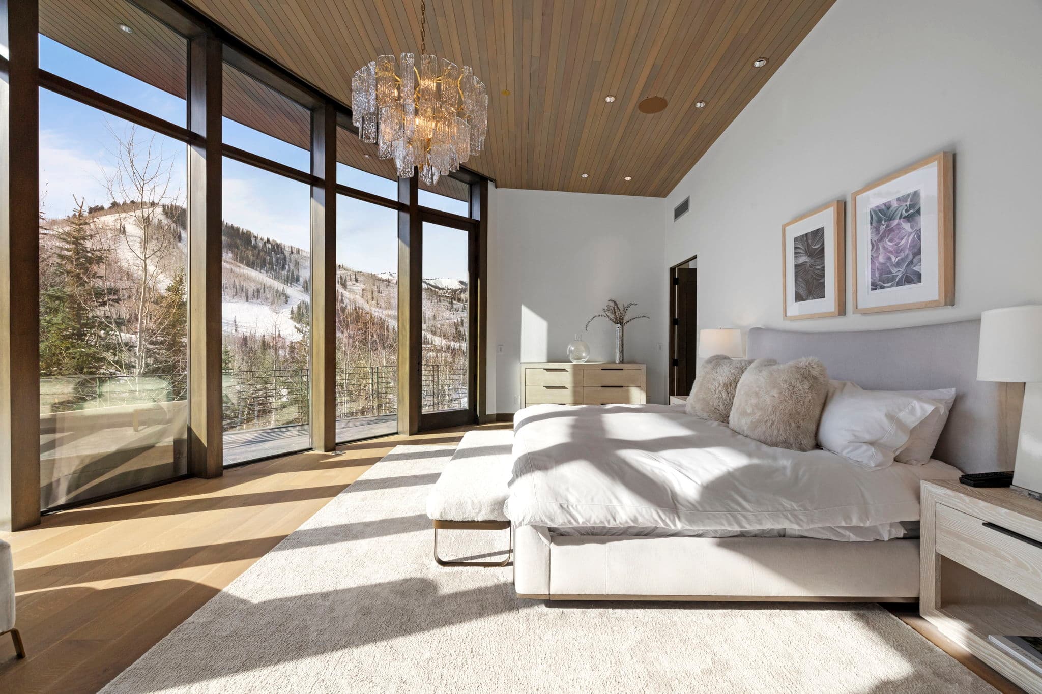 A bedroom with floor-to-ceiling windows and a chandelier.