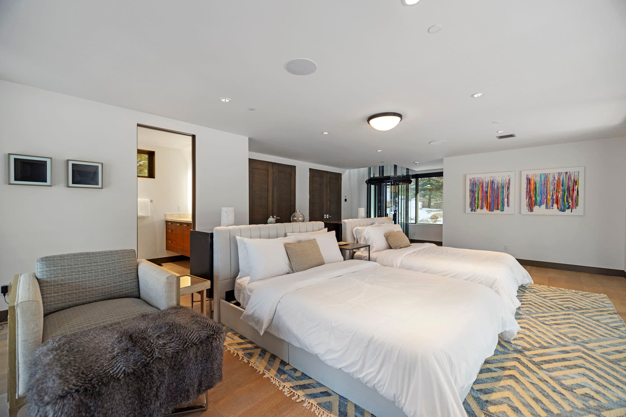 A bedroom with two beds and a chair.