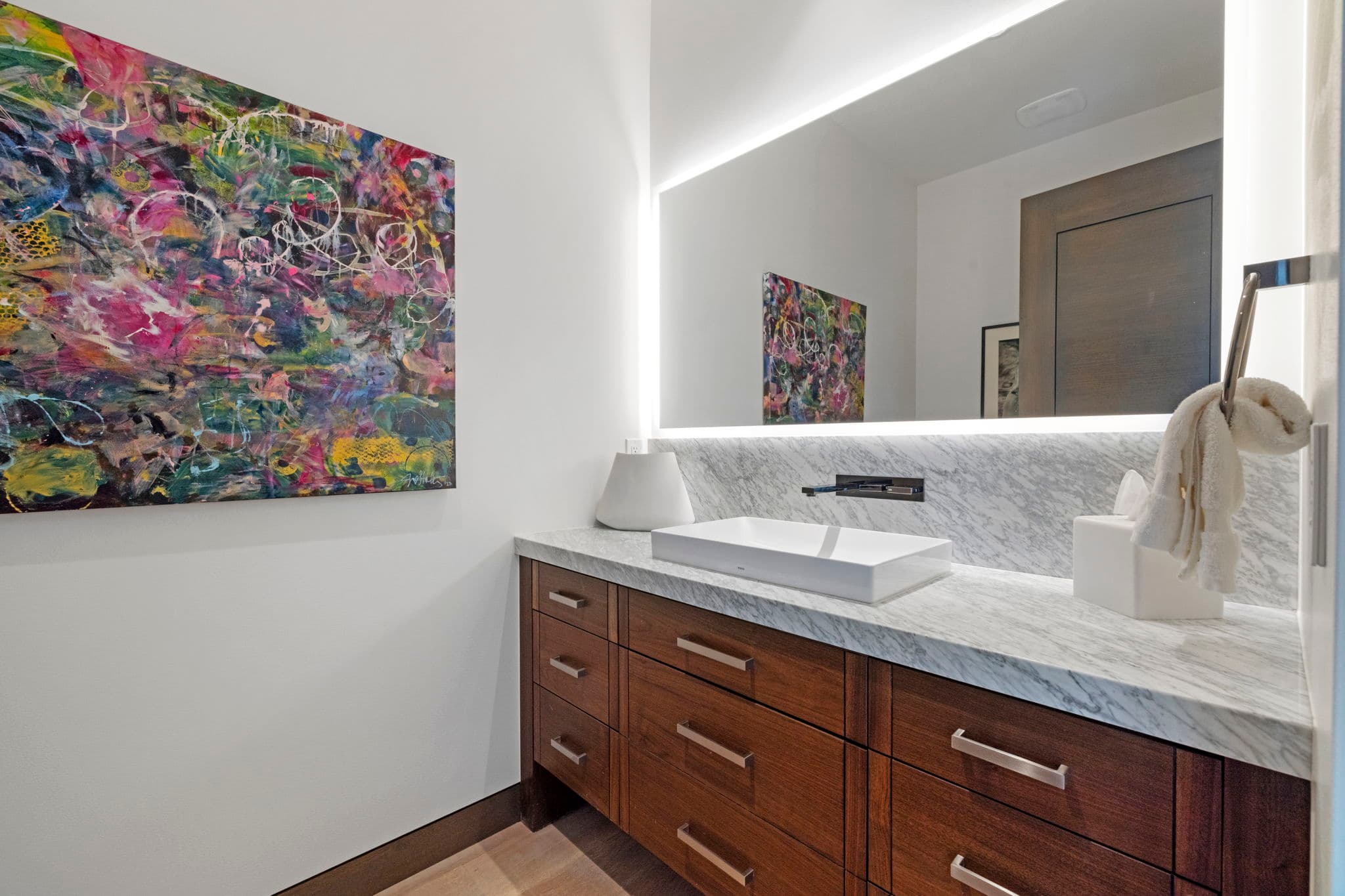 A bathroom sink with a mirror and artwork on the wall.