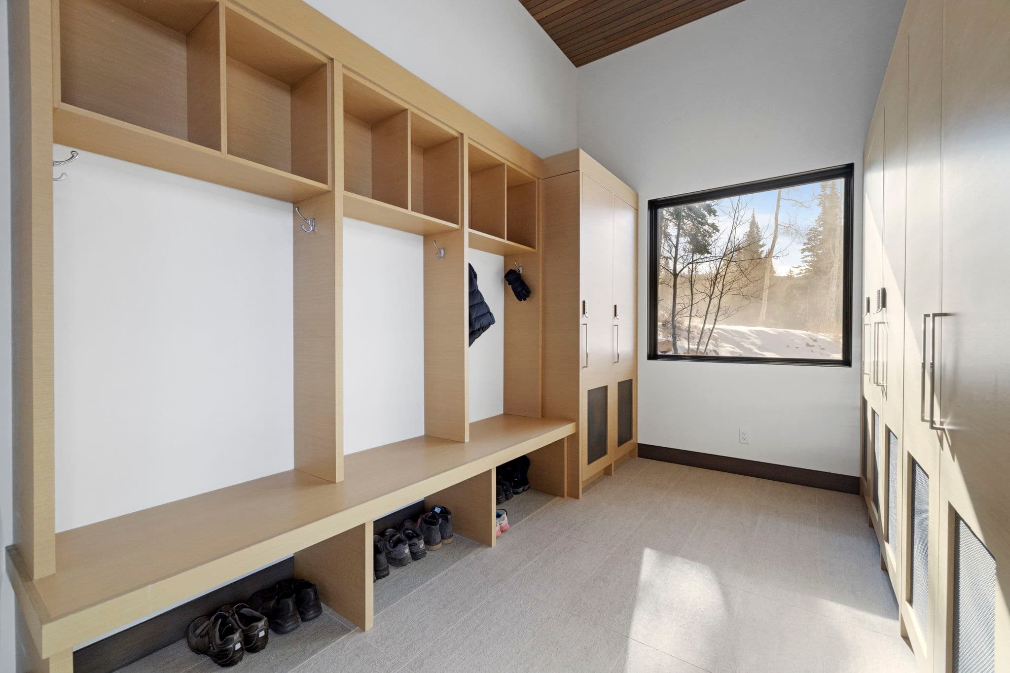 A view of a mudroom with storage for coats and shoes.