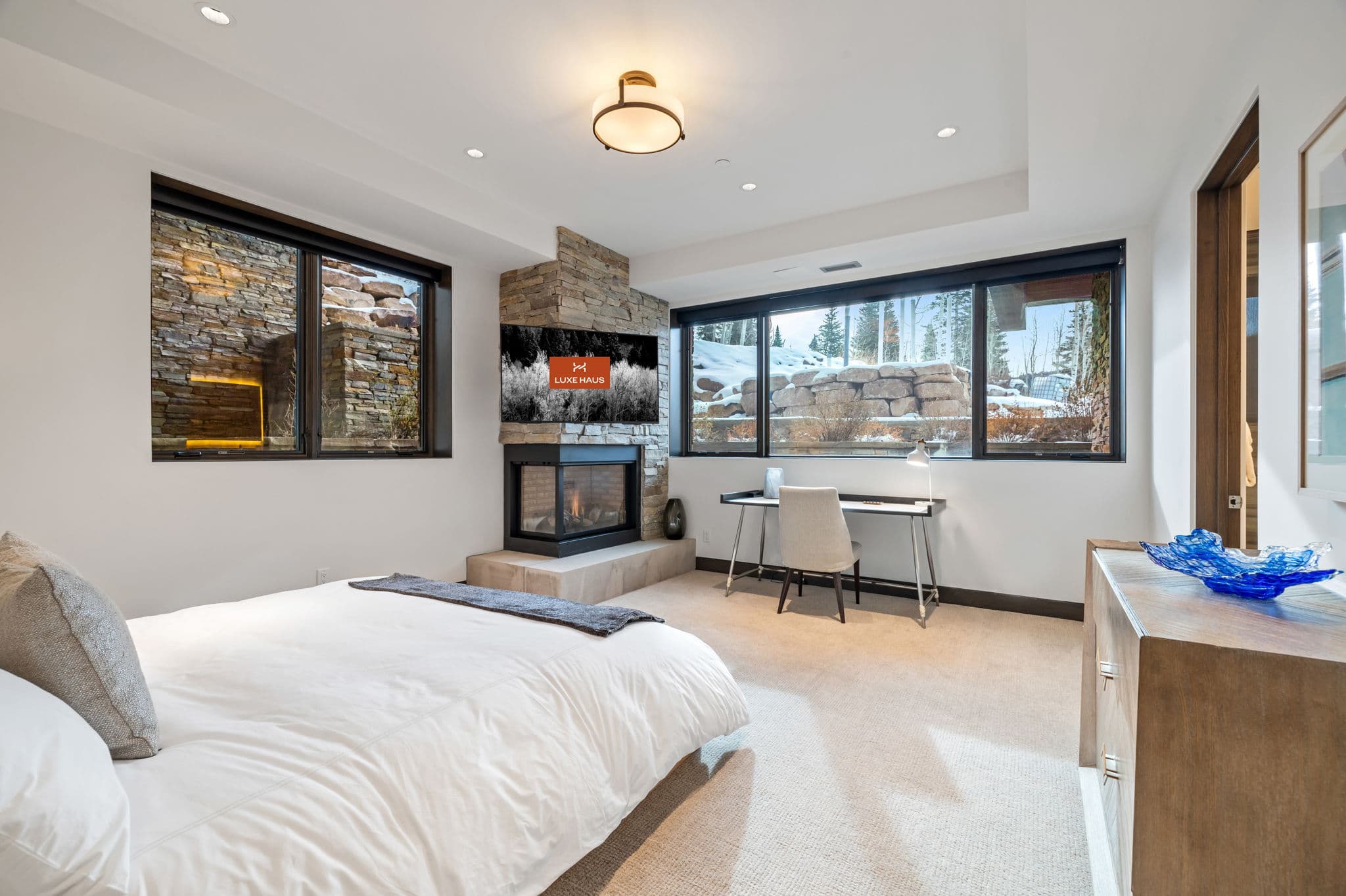 A bedroom with a bed, a fireplace, and a desk.