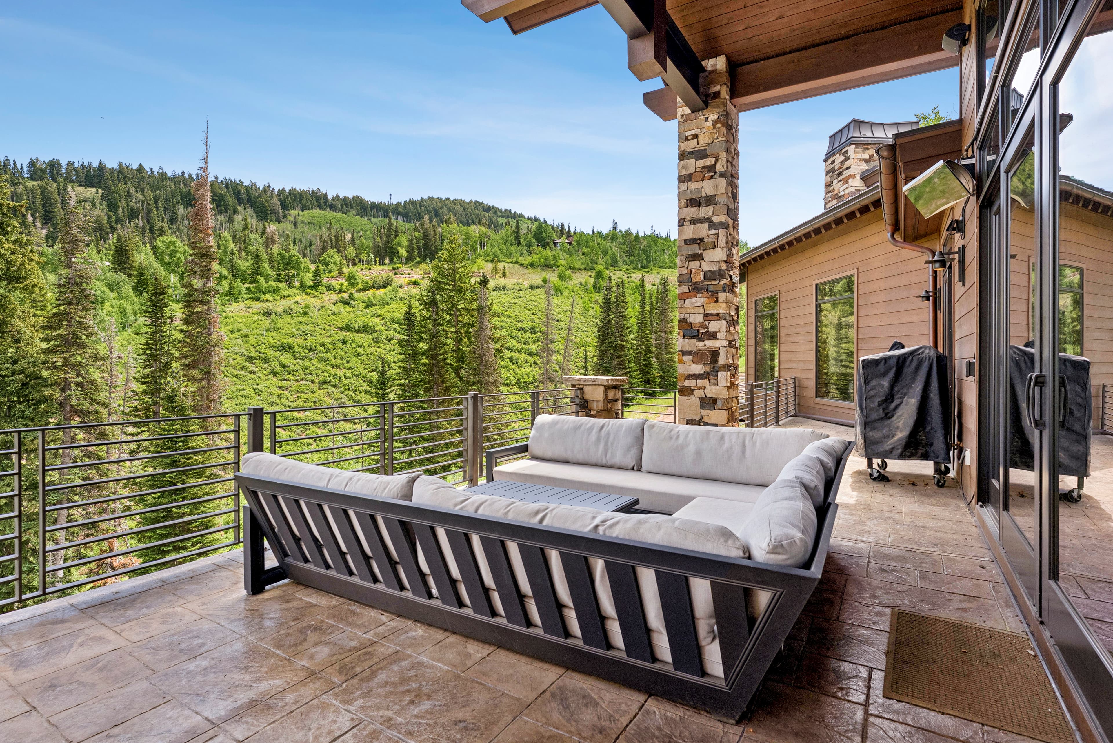the deck at grandview, covered with outdoor grill and large overstuffed sectional. you can see the mountains of park city from the deck.