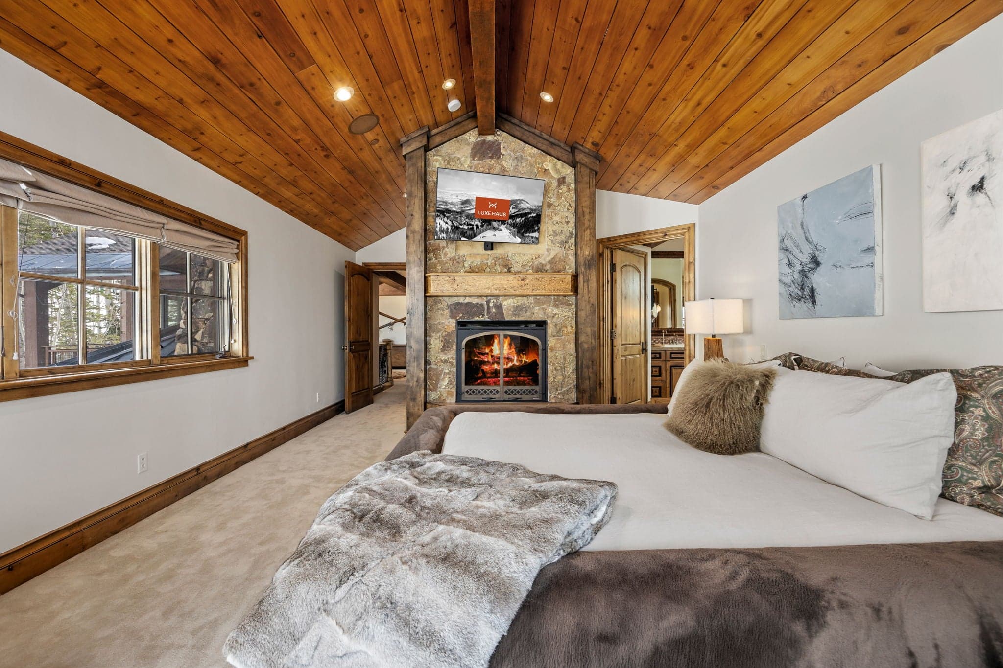 a view of the grand primary suite with fireplace and TV