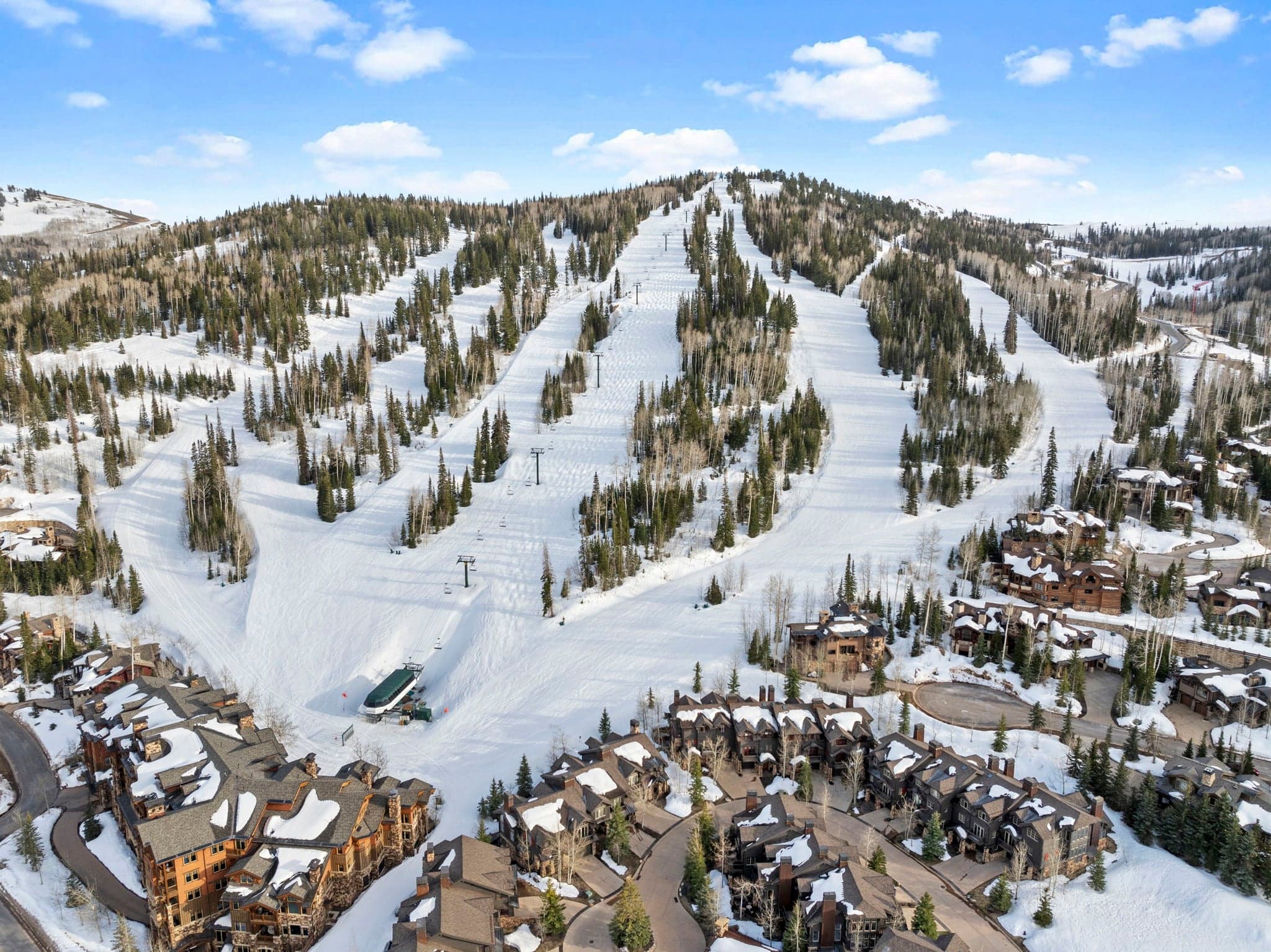 multiple ski runs visible from areal view of dear valley with home right alongside the farthest run to the right