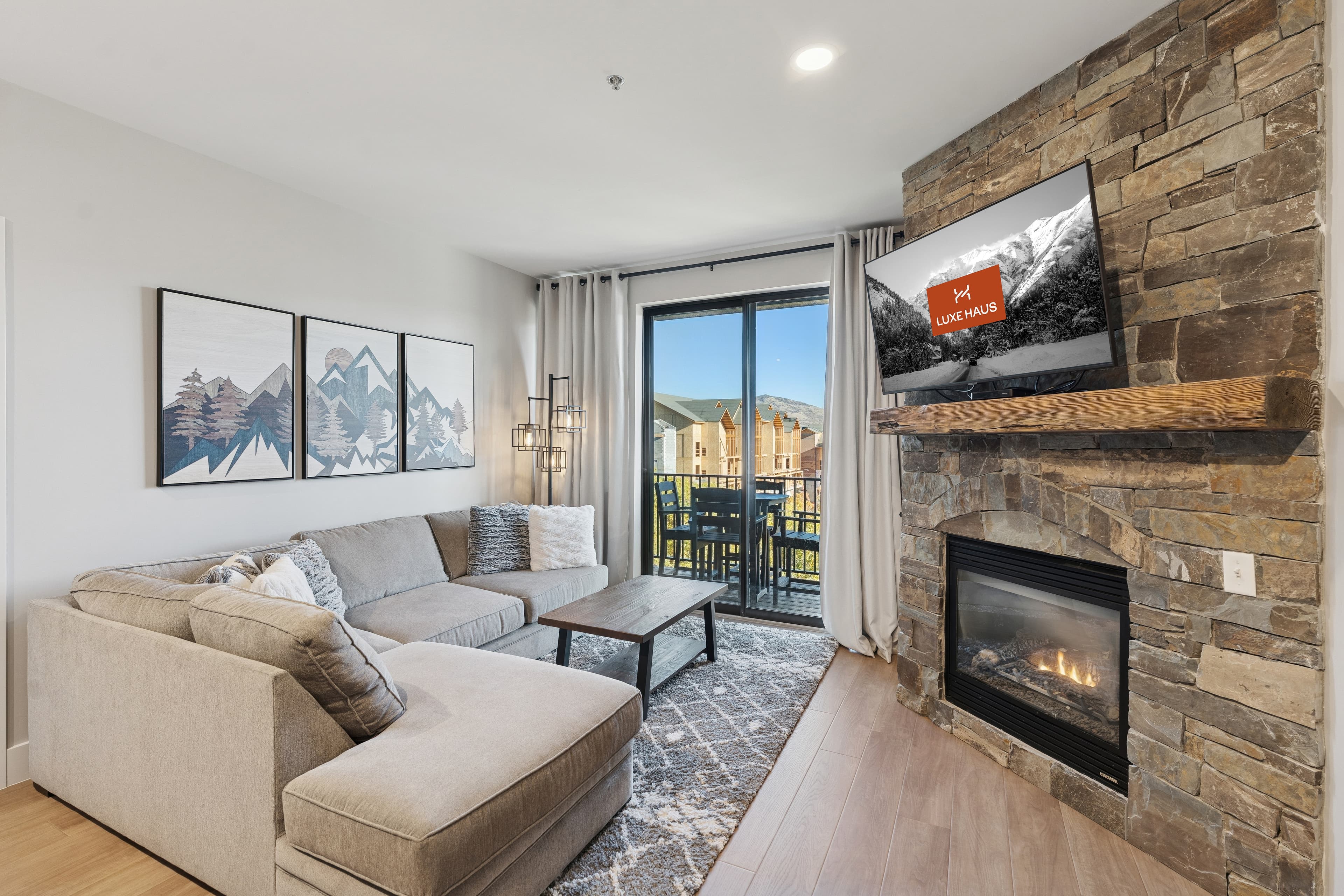 The living room at The Mason with a fireplace, large flat screen TV and mountain views
