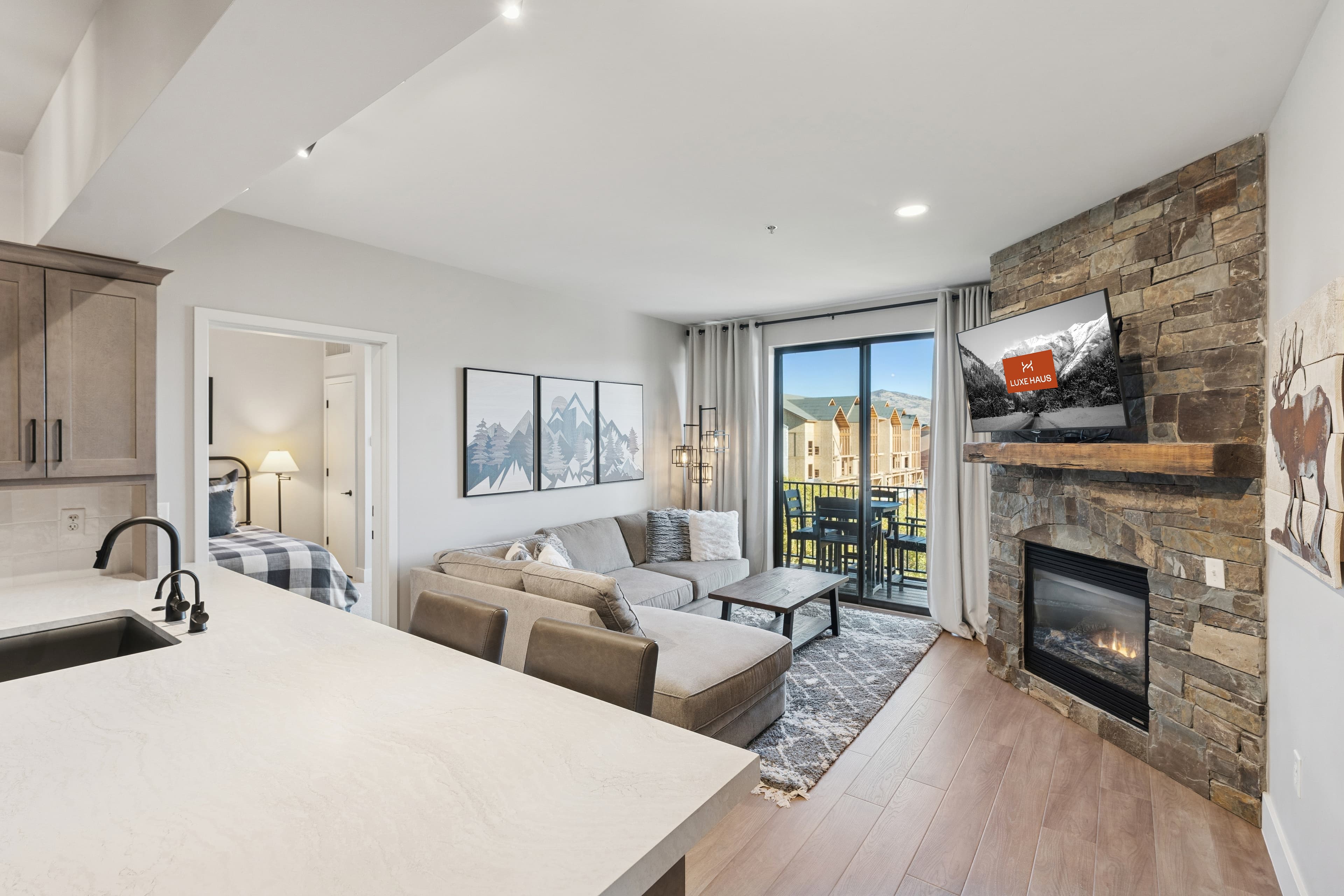 Stylish Park City condo living area with stone fireplace, open floor plan, and private balcony access.